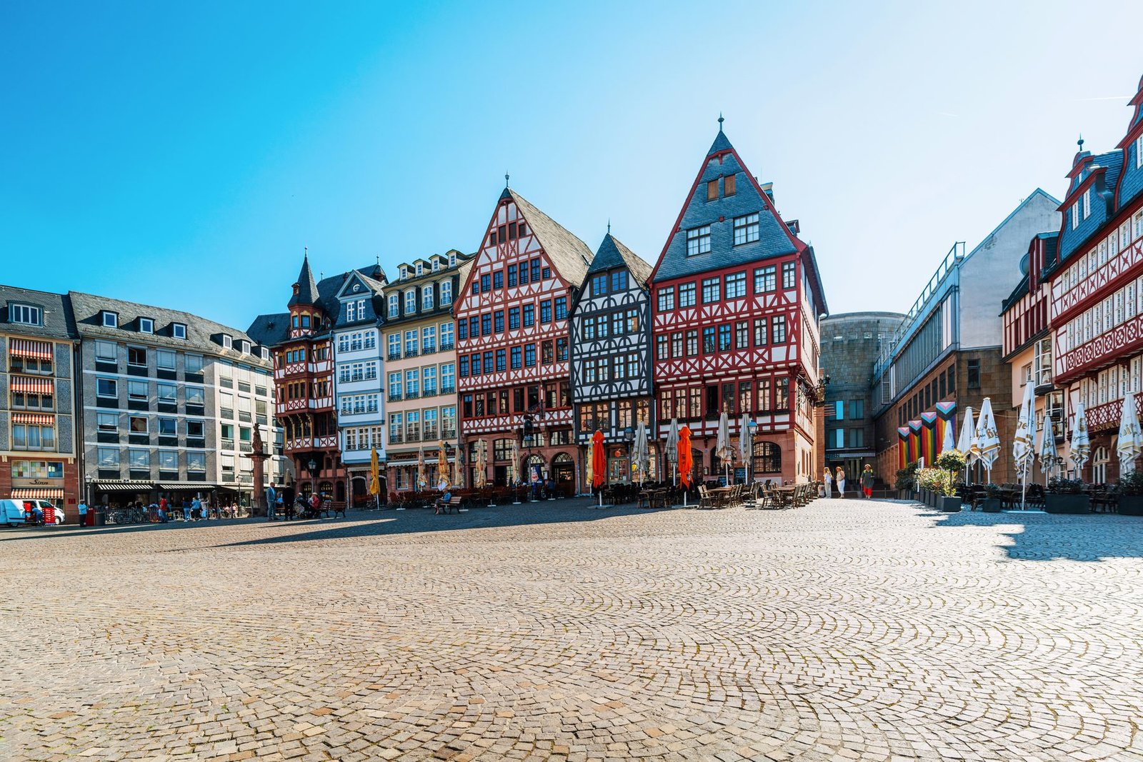 A cobbled square lined with gabled half-timbered houses under a blue sky